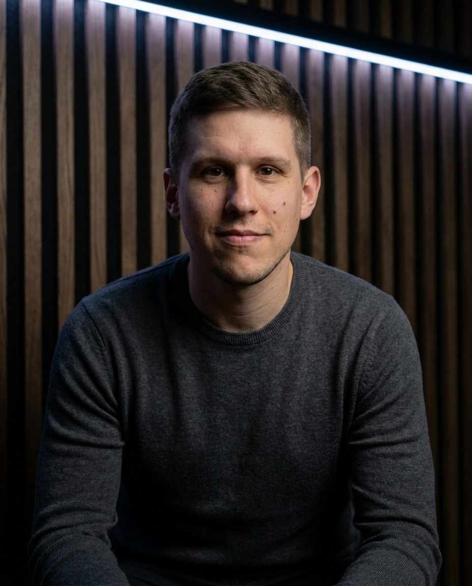 Julian Bleß in front of a dark wooden slat wall